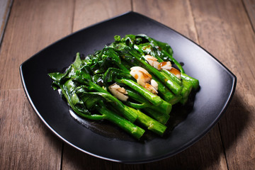 Kale fried in oyster sauce on wooden background