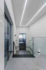 Clean white stairway staircase with glass railing in corridor in office building 