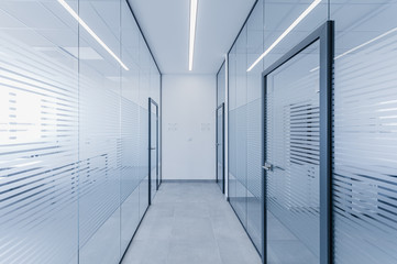 Empty modern hall corridor between glass walls in office building