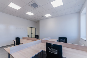 Interior of small new empty office space with desks and chairs
