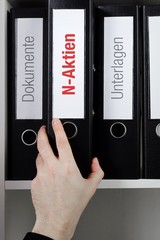 N-Aktien – Finanzen/Statistik. Ordner im Büro-Regal. Hand greift Unterlagen im Schrank....