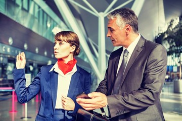 Portrait of businessman showing ticket on smartphone with airport staff 
