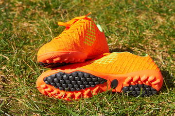 children orange soccer shoes,pair of soccer shoes for training on the soccer field - Powered by Adobe