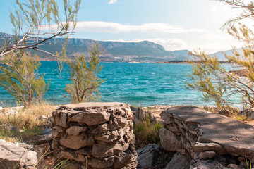 Fototapeta na wymiar Old stone and chairs made from rocks hidden in a small cove in split, croatia. Warm summer day with crystal clear sea in the beackground. Tropical travel paradise