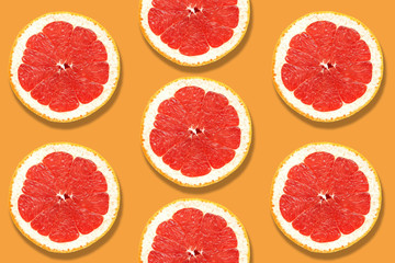 Fresh slices of grapefruit close-up on a yellow-mustard color background. Top view, flat lay.