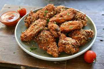 Baked chicken wings with sesame seeds. Ketchup and chili sauce. Free space for text. Wooden...