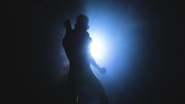 Young muscular and sexy man dancing in the shadow on the background of a spotlight