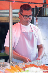 street hawker man working with his delicious meatball skewer street food; concept of asian street...