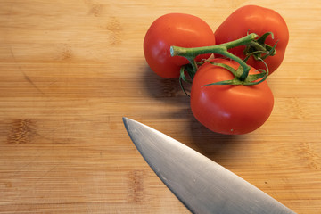 Frische Rispentomaten auf Holz. Mit Messer. Kochen, Zubereiten 