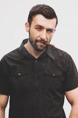 Obraz premium Handsome stylish man smokes a cigar.