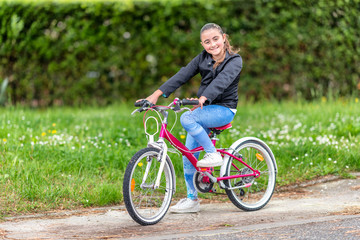 Naklejka premium Happy young girl biking in the city park