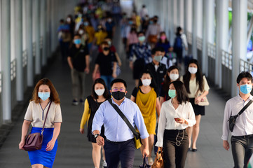People wearing surgical mask walking in subway station during rush hour