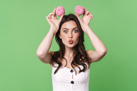 Image of excited young woman making kiss lips and fun with marshmallows
