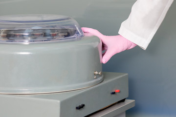 Hands of nurse switching the applianing on or off centrifuge machine, wearing protective gloves in...