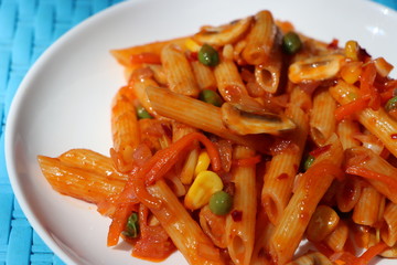 Penne pasta in tomato sauce with peas, button mushrooms, tomatoes and vegetables, Red mushroom wholegrain pasta