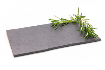 Fresh rosemary herb on a slate board with a white background
