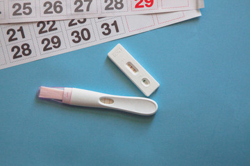 Positive pregnancy test and a calendar on the blue background. Pregnancy concept. 