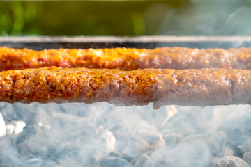 Traditional Turkish Adana  Kebap on the grill with skewers  for dinner. Turkish cuisine food culture in Turkey. Adana kebab on the mangal in nature. Picnic.