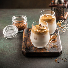 Korean trendy drink dalgona coffee from instant coffee, milk and ice on old wooden board. Modern drinks concept with copy space.