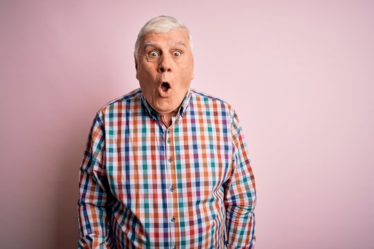 Senior handsome hoary man wearing casual colorful shirt over isolated pink background afraid and shocked with surprise and amazed expression, fear and excited face.
