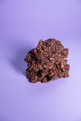 Oatmeal cookies pile with chocolate powder and peanut butter on purple background. Healthy snack. Top view. Vertical picture.