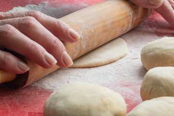 The process of rolling the dough with a wooden rolling pin, cooking bread at home.