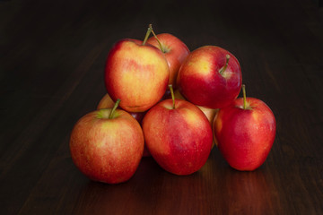 A beautiful red apples on the surface of a wooden tabletop made of boards with a dark textured surface.