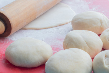 Cooking tortillas from dough, wooden rolling pin and balls of dough on the table.