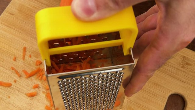 Hand rubbing carrot on grater. Reverse side of grater.