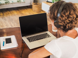 Fototapeta premium woman having a video conference on her laptop with black screen wearing a headset with notepad and mobile phone on the desk in her home office 