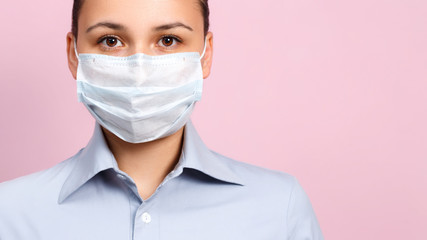 Studio portrait of young woman wearing a face mask, looking at camera, close up, isolated on pink background. Flu epidemic, dust allergy, protection against virus
