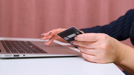 female hands make a purchase on the Internet using a laptop, payment by card, close-up.