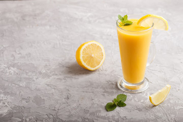 Glass of lemon drink on a gray concrete background. Side view
