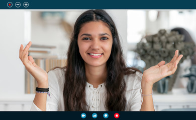 Portrait of young attractive businesswoman making video call at home office.