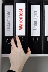 Warentest – Finanzen/Statistik. Ordner im Büro-Regal. Hand greift Unterlagen im Schrank. Beschriftung mit Wort