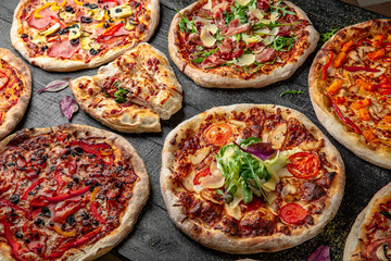 Tasty hot italian pizzas set on black wooden table. Pizzeria menu. Concept poster for Restaurants or pizzerias