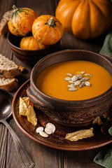 Home made pumpkin and carrot cream soup with seeds in old brown bowl. Healthy vegetarian food concept.