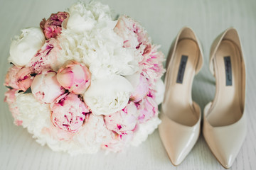 Obraz na płótnie Canvas Pair of elegant and stylish bridal shoes with a bouquet with roses and other flowers.