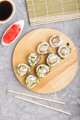 Japanese maki sushi rolls with green onion on wooden board on a gray concrete background. Top view, close up.
