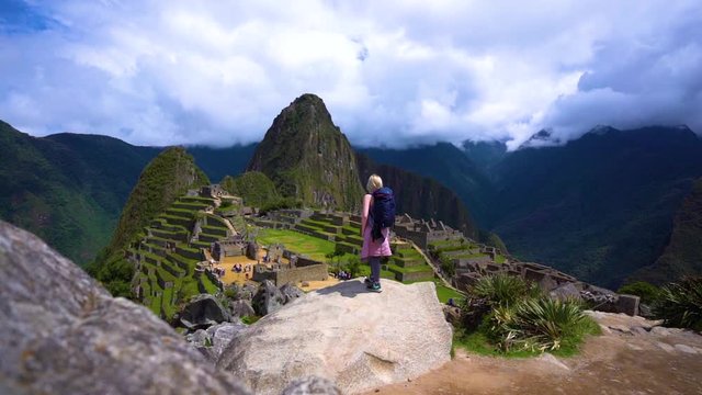 Young girl standing on a rock looking out over the ancient city Machu Picchu