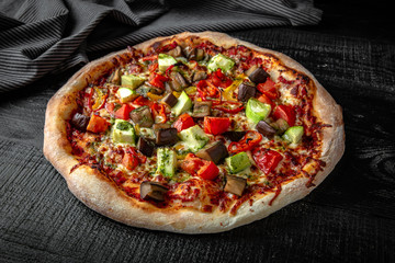 Tasty hot italian pizza vegetarian with eggplant, zucchini, tomatoes on black wooden table. Pizzeria menu. Concept poster for Restaurants or pizzerias