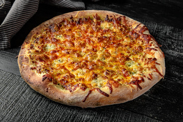 Tasty hot italian four cheeses pizza on black wooden table. Pizzeria menu. Concept poster for Restaurants or pizzerias