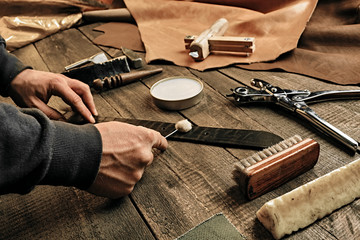 Working process of the leather belt in the leather workshop. Man holding tool. Tanner in old...