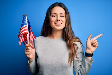 Young beautiful brunette patriotic woman holding american flag celebrating 4th of july very happy...