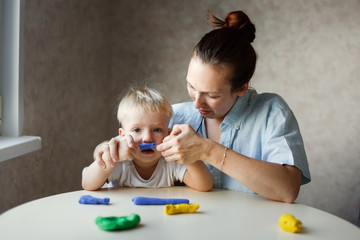 Naklejka premium mother sculpts with baby from children's dough