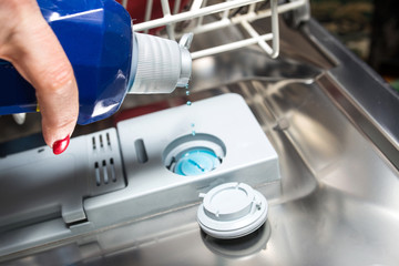 Dishwasher service. Pouring rinse liquid closeup.