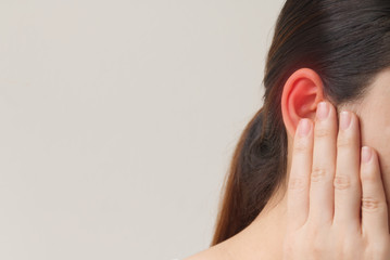 Young female suffering from ear pain, Tinnitus and otitis, she use hand touching at her ear.