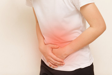 Young woman suffering from stomach ache on gray background