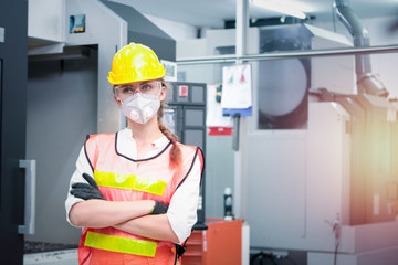 Industrial engineer worker female wearing helmet, safe glasses and mask, standing with arms crossed at manufacturing plant factory, young beautiful woman working in industry