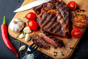 Fresh juicy ribeye steak with a set of spices on a cutting board